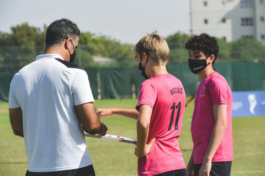 Coach spricht mit Spielern auf dem Spielfeld - Ratgeber Fußballmanagement Studium