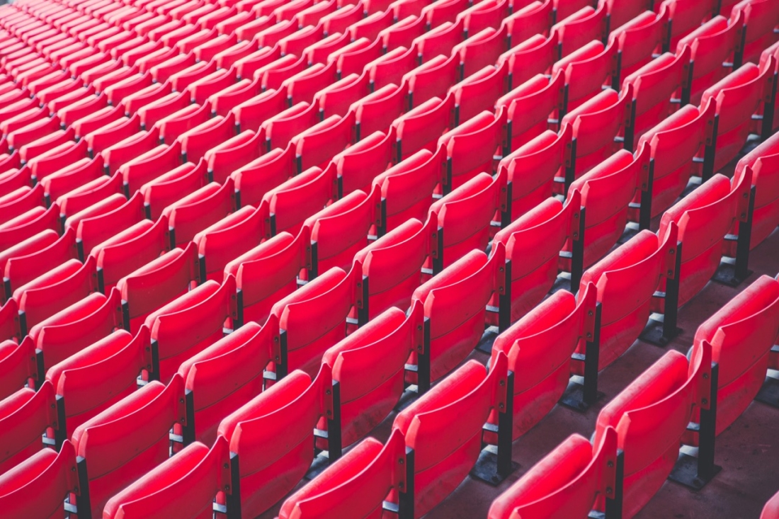 Mehrere leere rote Sitzreihen eines Stadions - Ratgeber Fußballmanagement Studium