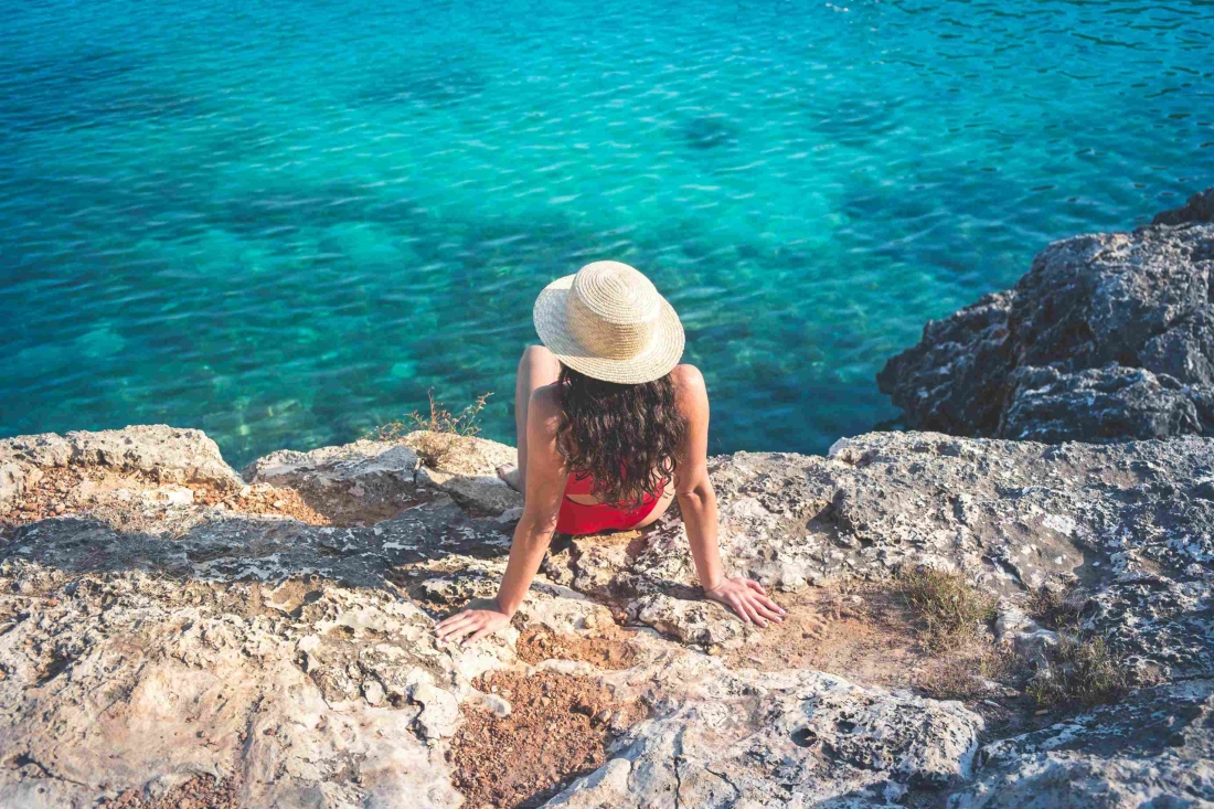 Mädchen im Bikini und mit Sonnenhut am Meer- Ratgeber Studieren in Spanien: Campus M University.