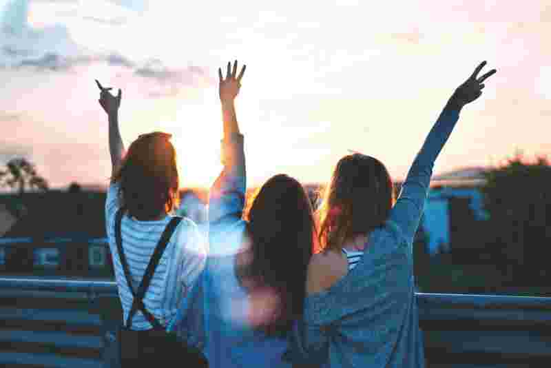 Drei glückliche junge Menschen schauen den Sonnenuntergang an - Ratgeber Studium im Tourismus: Campus M University.