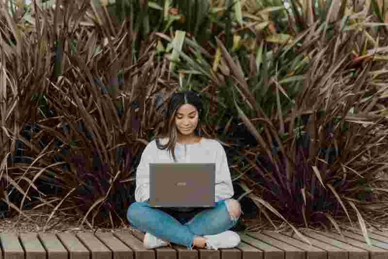 Junge Frau mit Laptop auf dem Schoß - Ratgeber Campus M University Kosten.