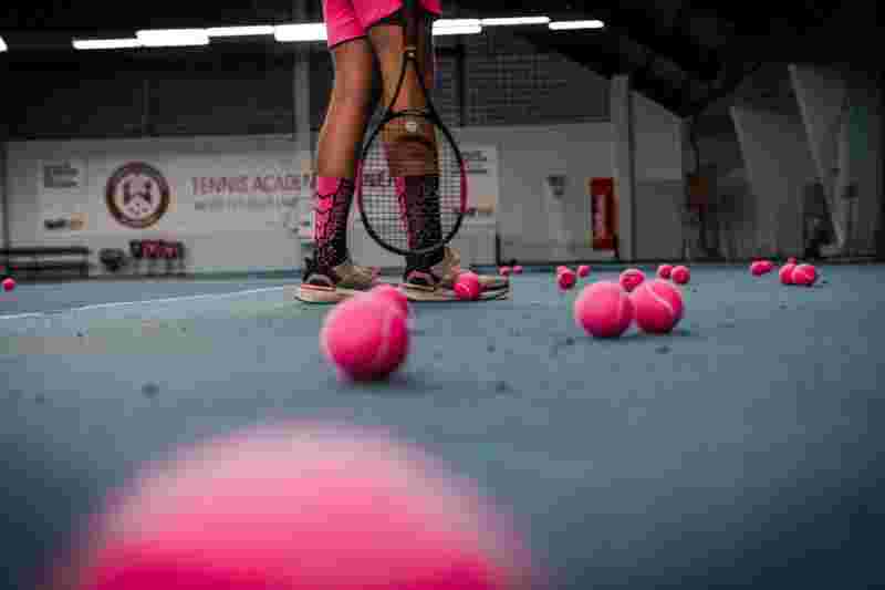 Beine einer Tennisspielerin und pinke Bälle am Platz - Ratgeber Sportpsychologie Studium Campus M University