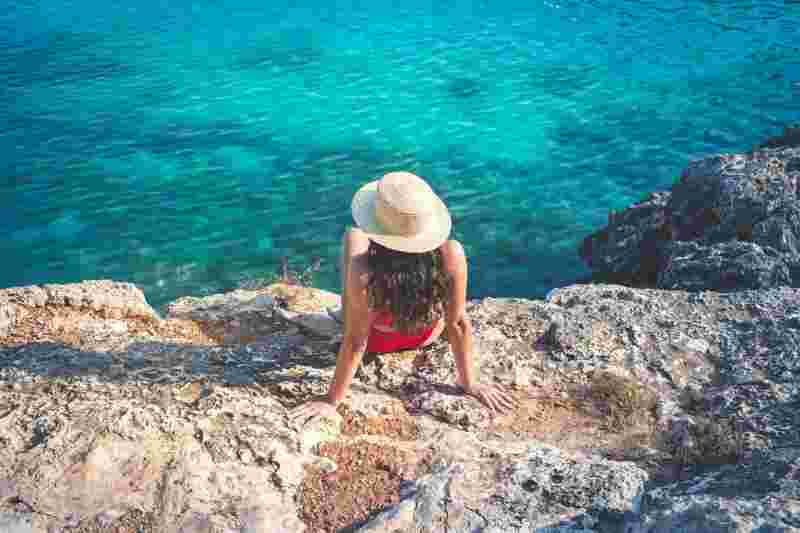 Mädchen im Bikini und mit Sonnenhut am Meer- Ratgeber Studieren in Spanien: Campus M University.