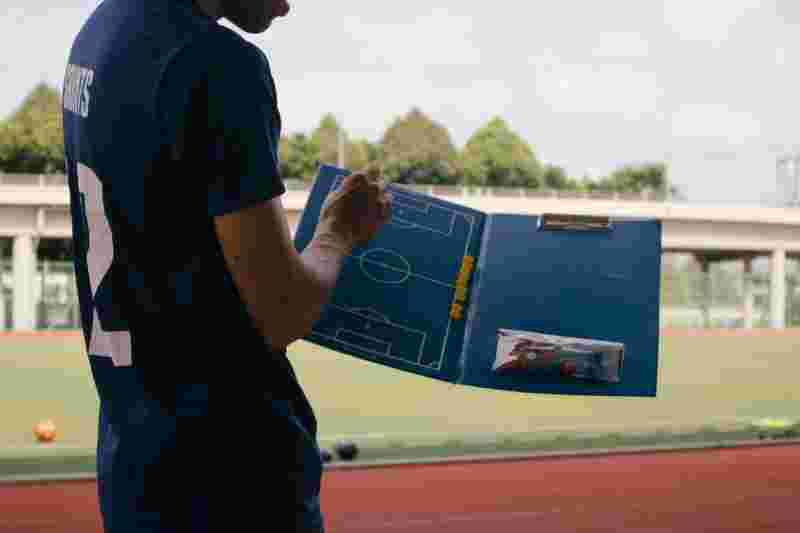 Trainer am Rande des Spielfeldes mit einer Tafel - Ratgeber Fußballmanagement Studium