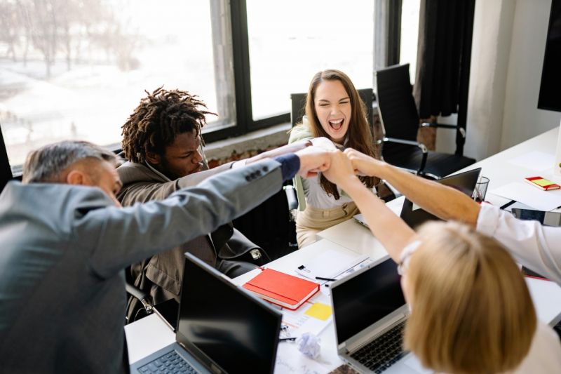 Glückliche Studentengruppe, Fistbump mit Professor - Ratgeber Brand Management Studium: Campus M University.