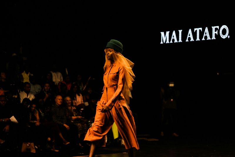 Weibliches Modell im orangenen Kleid auf dem Runway - Ratgeber Fashion Business Studium: Campus M University