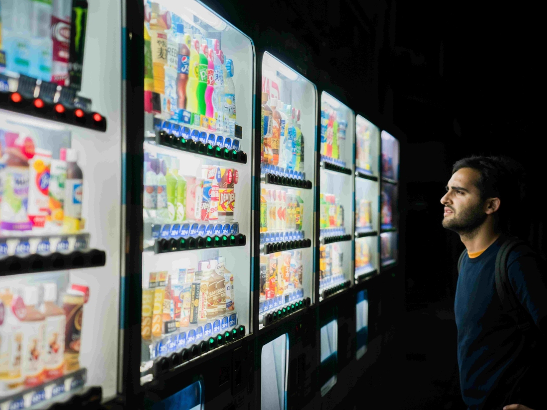 Eine Person steht vor Getränkeautomaten und entscheidet sich, was für psychologische Aspekte im Verkauf steht – Karrierechancen nach dem Wirtschaftspsycholgie Studium.