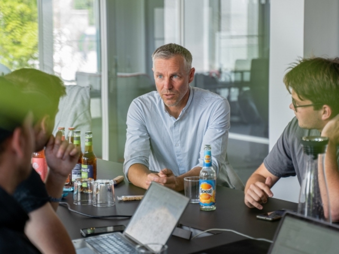 Mentor und Studierende bei einem Praxisprojekt an einem Tisch - Ratgeber Social Media Studium: Campus M University.