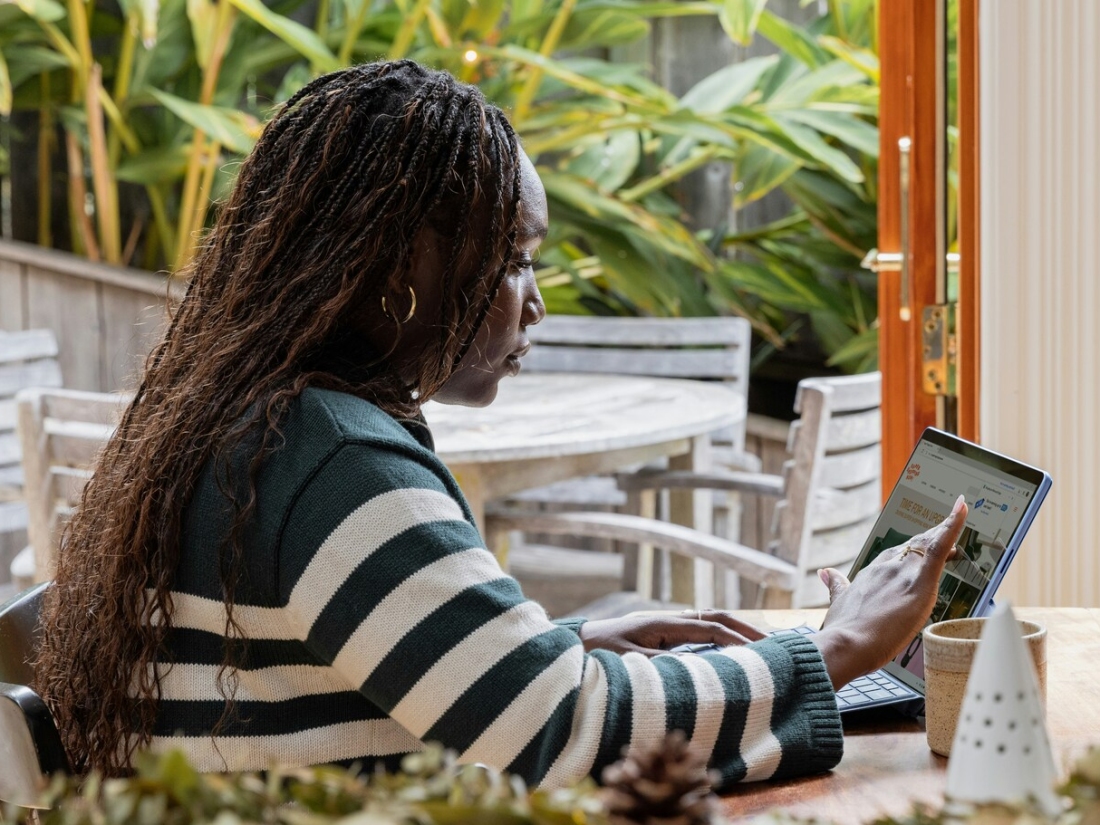 Frau arbeitet an einem Laptop auf einer Terrasse - Ratgeber Studium im Tourismus: Campus M University.