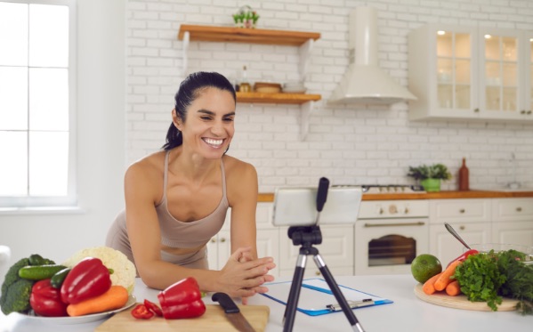 Fitnessinfluencerin in der Küche mit Gemüseplatte vor der Kamera- Ratgeber Studium zum Ernährungsberater: Campus M University.